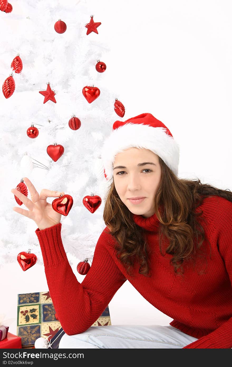 Beautiful young woman wearing santa hat holding an heart