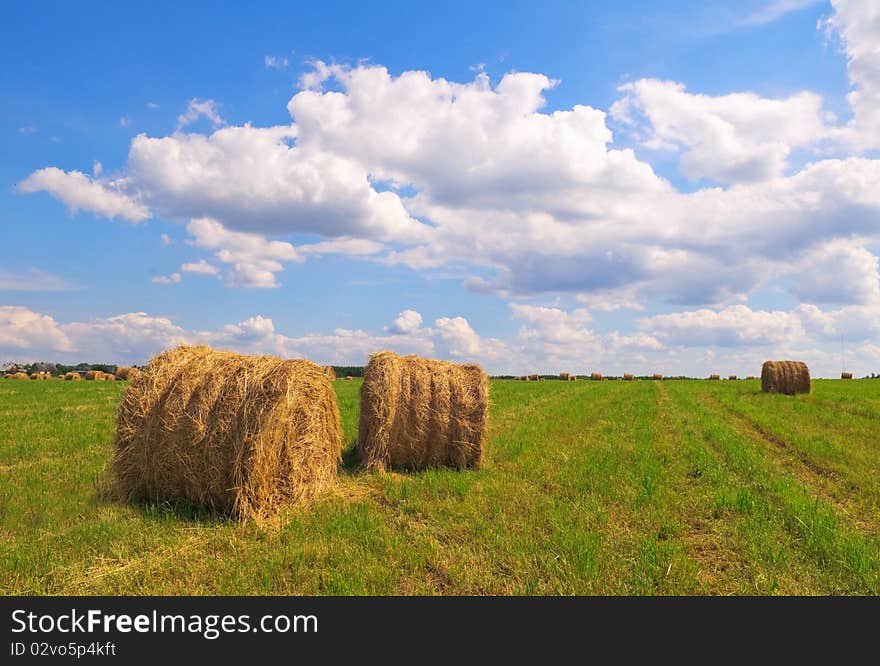 Straw bales on field against sky