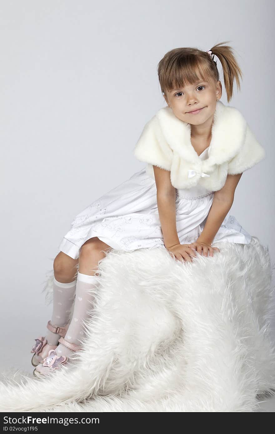 Full lenght portrait of an adorable little girl, sitting in studio, winter setup. Full lenght portrait of an adorable little girl, sitting in studio, winter setup