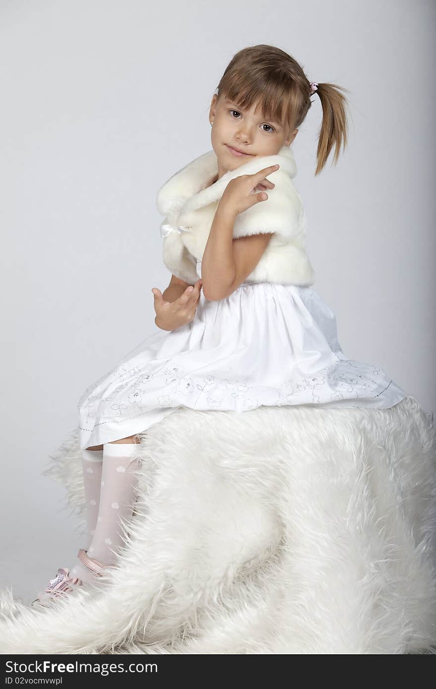 Full lenght portrait of a cute little girl sitting, studio image, winter setup. Full lenght portrait of a cute little girl sitting, studio image, winter setup