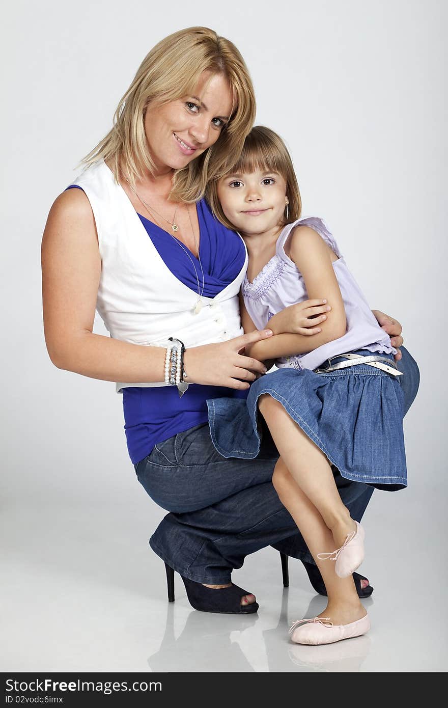 Full length portrait of two, beautiful young mother and daughter, smiling, studio image. Full length portrait of two, beautiful young mother and daughter, smiling, studio image