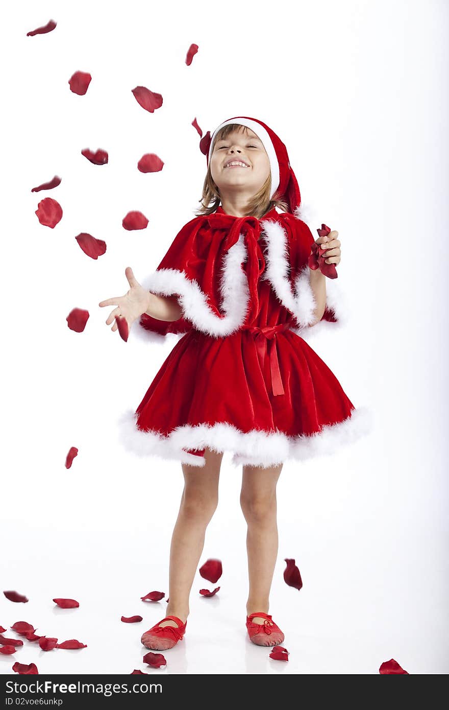 Full length portrait of a little Miss Santa or Santa's helper, joyful about a rain of rose petals. Studio image. Full length portrait of a little Miss Santa or Santa's helper, joyful about a rain of rose petals. Studio image