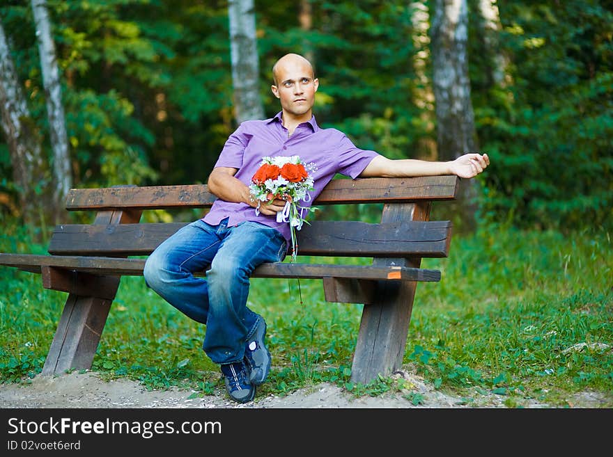 Photo of handsome guy with bouquet waiting for his girlfriend outside