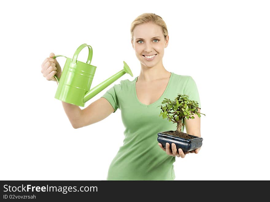 Young woman watering a bonsai tree; concepts: giving life, the beginning