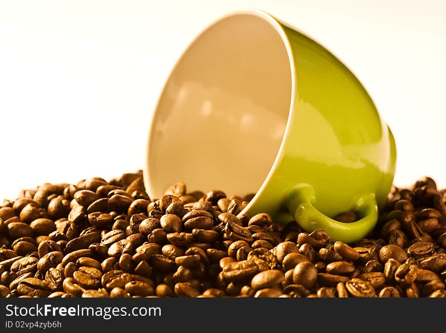 Green cup of coffee with much brown beans