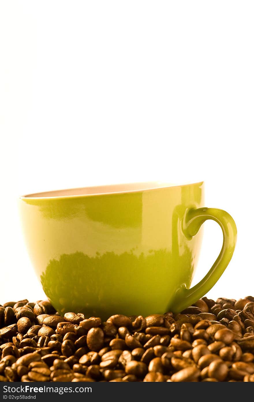 Green cup of coffee with much brown beans