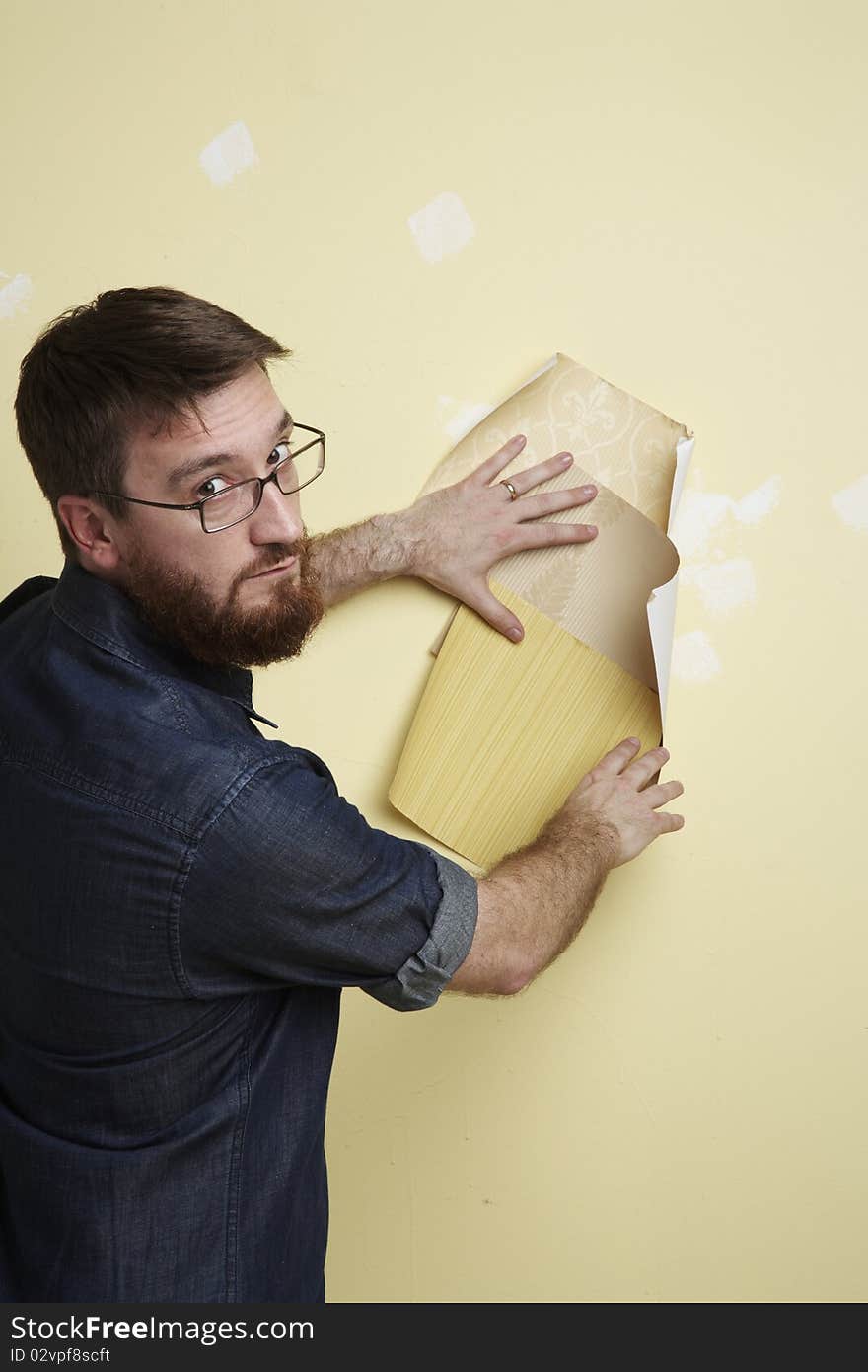 Man beard looking at three wallpaper samples on a wall and looking over his shoulder. Man beard looking at three wallpaper samples on a wall and looking over his shoulder.