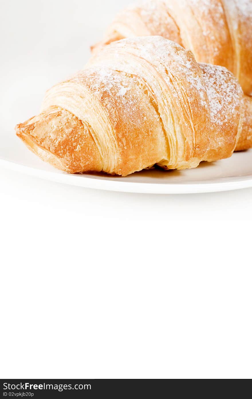 Fresh croissants on white plate with empty space below .