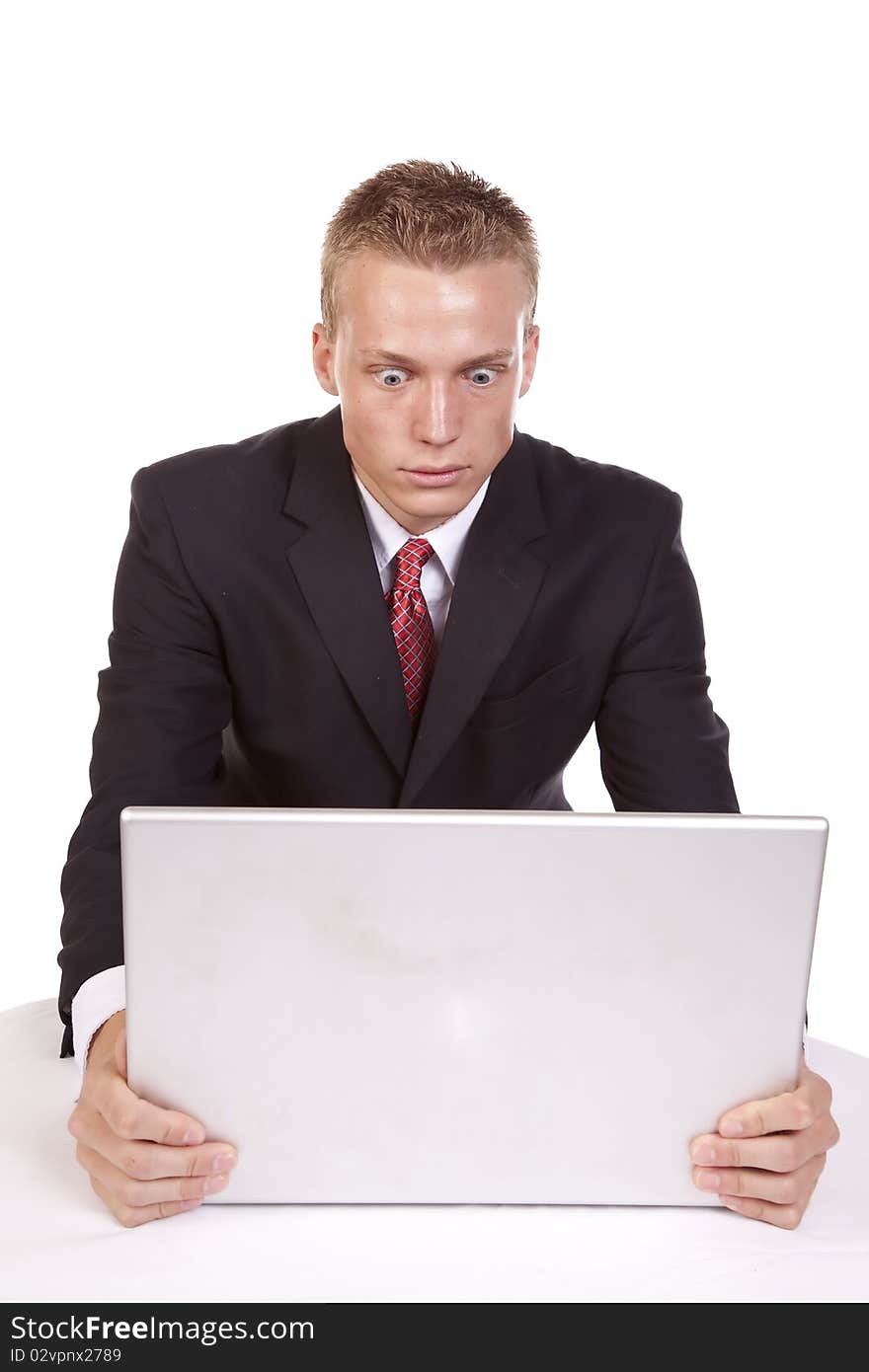 A young businessman sitting at his computer with a serious expression on his face. A young businessman sitting at his computer with a serious expression on his face.