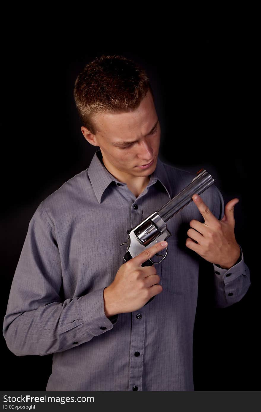 A young man looking down at his pistol in his hands. A young man looking down at his pistol in his hands.