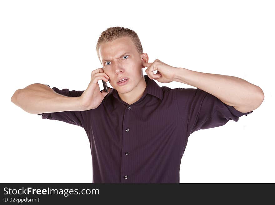 A young man plugging his ears trying to  listen to the person on his phone. A young man plugging his ears trying to  listen to the person on his phone.