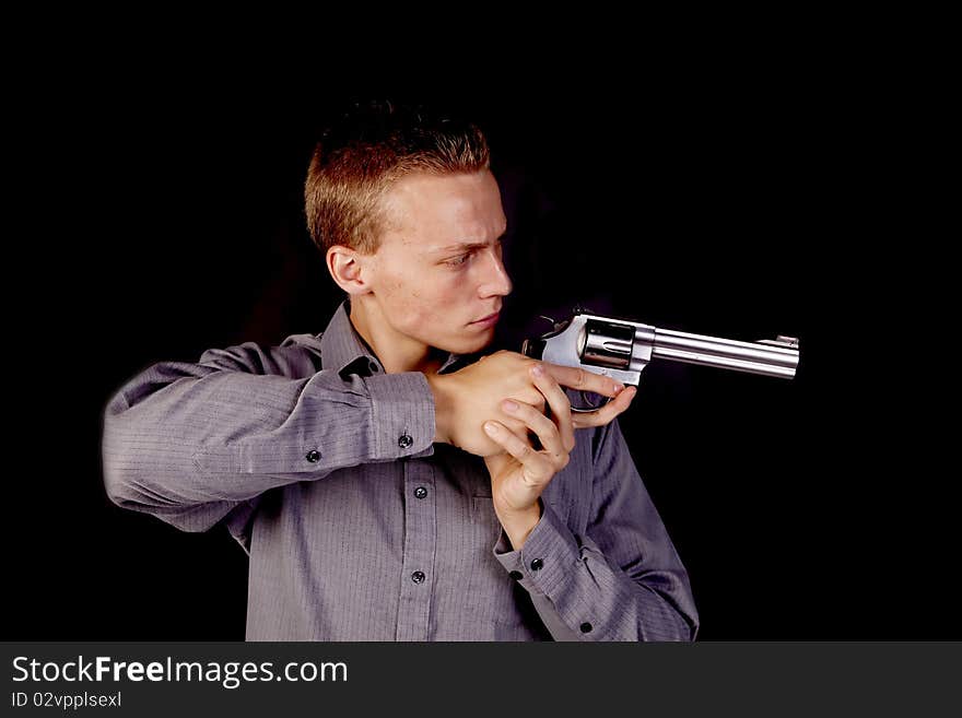 A young man pointing his gun with a black background. A young man pointing his gun with a black background.