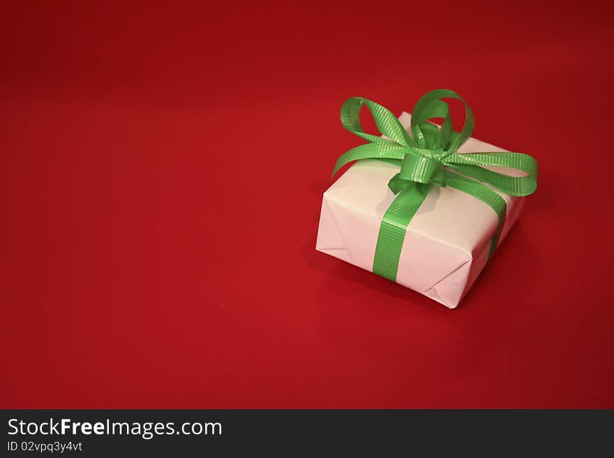 A green bow on a white package against a red background with room for copy. A green bow on a white package against a red background with room for copy