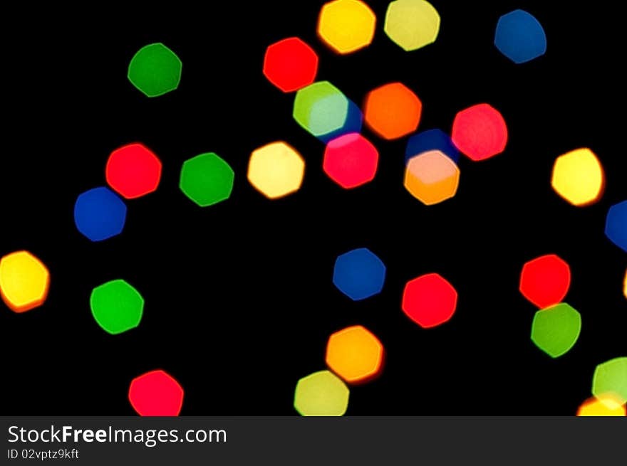 Multi-coloured polygonal stains are randomly scattered on a black background. Multi-coloured polygonal stains are randomly scattered on a black background