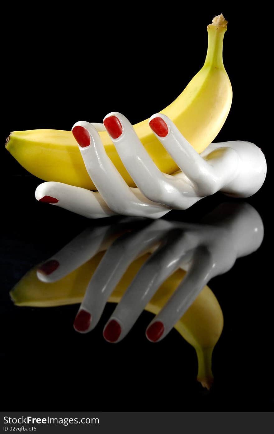 Hand and banana with reflection. Black background.