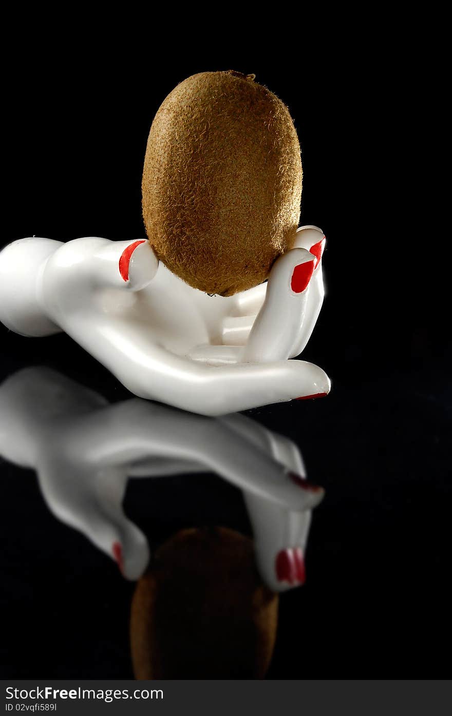 Kiwi in a white hand with reflection. Black background. Kiwi in a white hand with reflection. Black background.