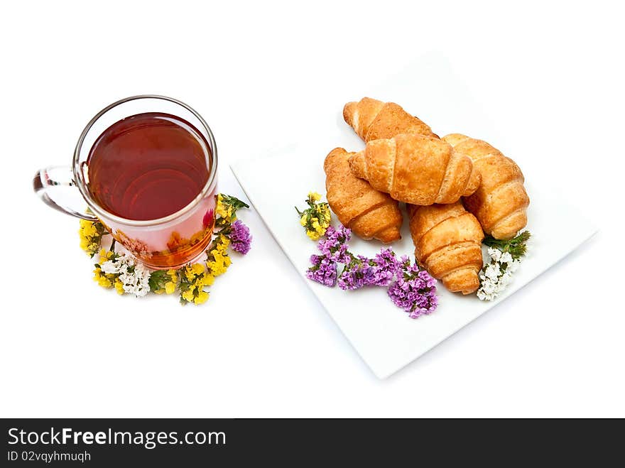 Croissants and hot tea with flowers isolated on white background