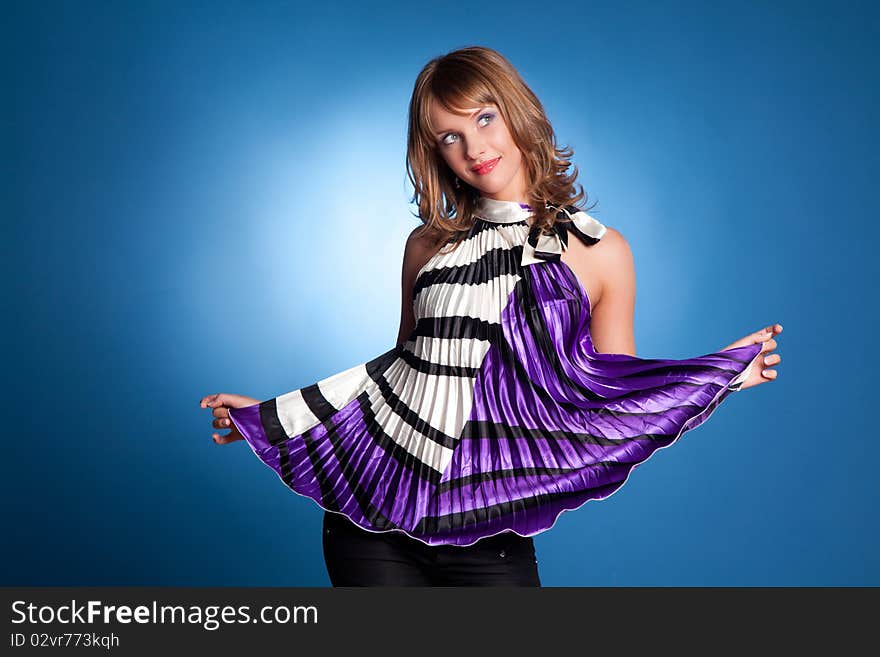 Beautiful girl in bright clothes on a blue background in studio