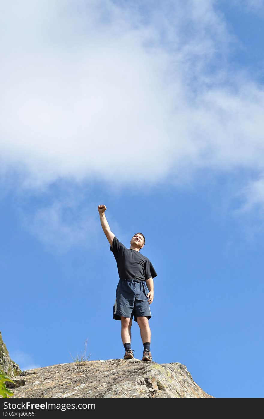 A young man stands on a cliff top