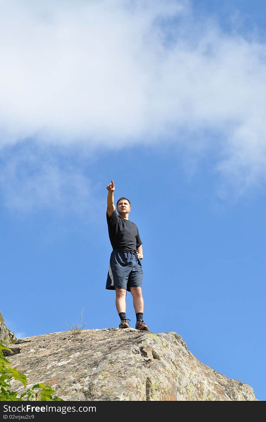 A young man stands on a cliff top