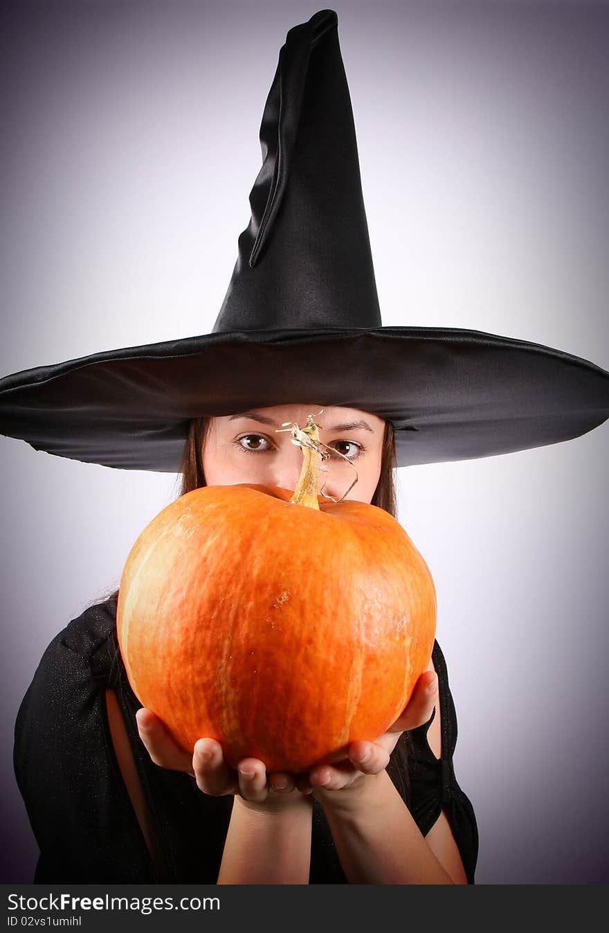 Young witch holding a pumpkin (focus on pumpkin). Young witch holding a pumpkin (focus on pumpkin)