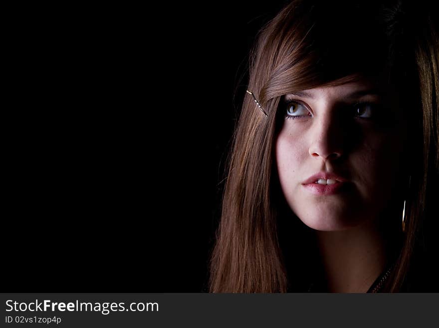 Teenage girl is looking in a corner isolated over black background. Teenage girl is looking in a corner isolated over black background.