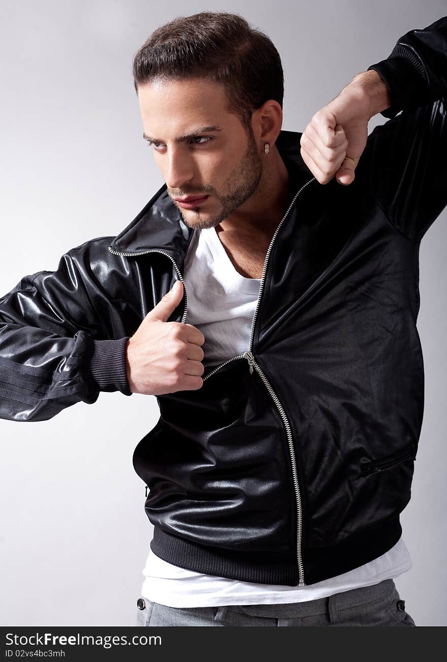 Smart male model giving movement with black jacket on a isolated grey background