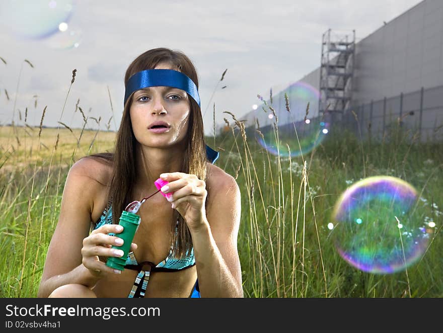 Wistful young woman blowing soap bubbles in summer day