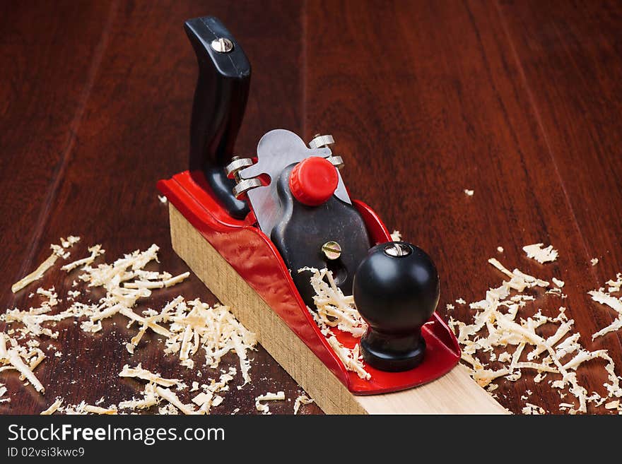 Red plane on brick and shavings on dark wooden background