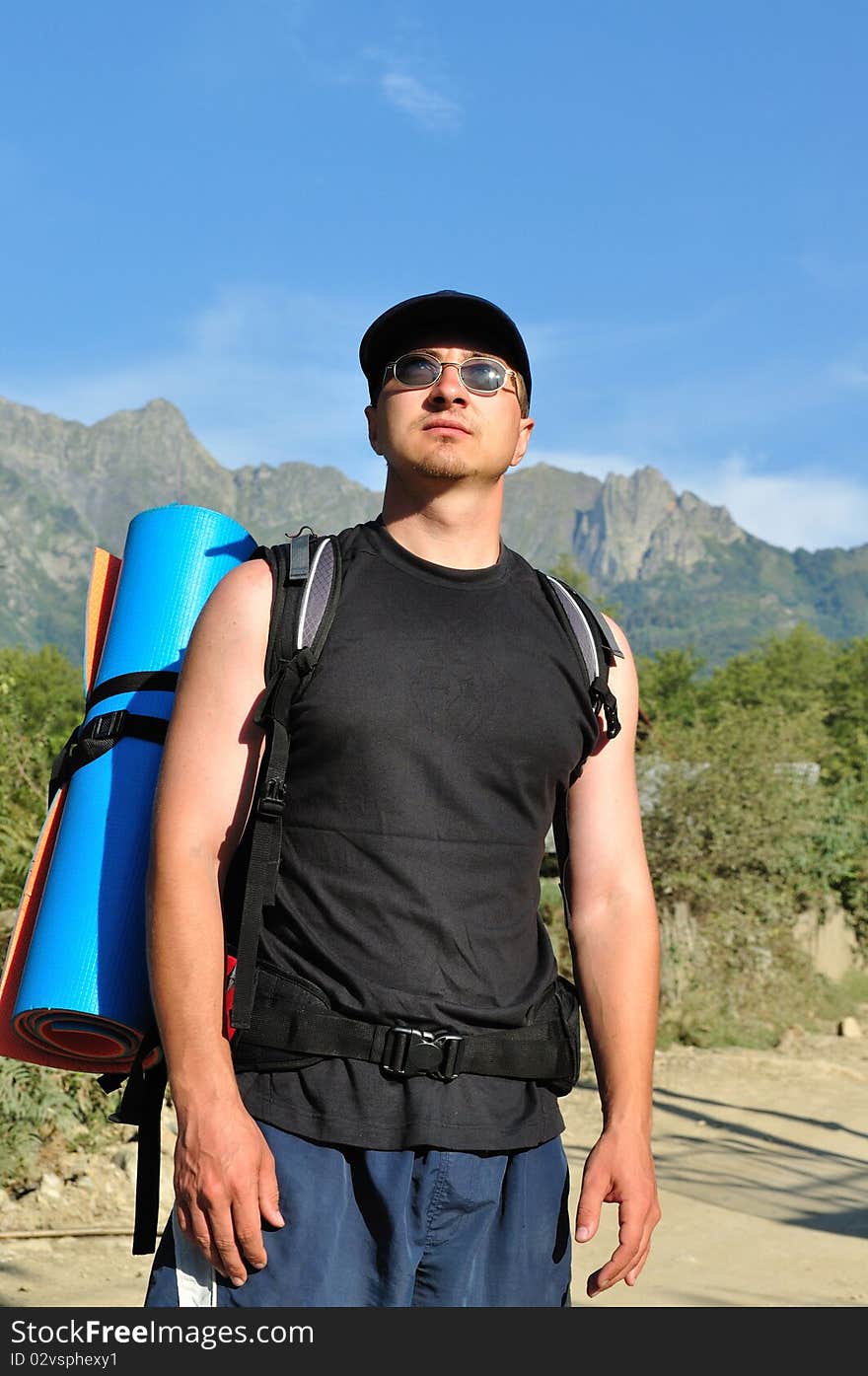 Tourist with a large backpack is a high mountain, on the way, full-face photos