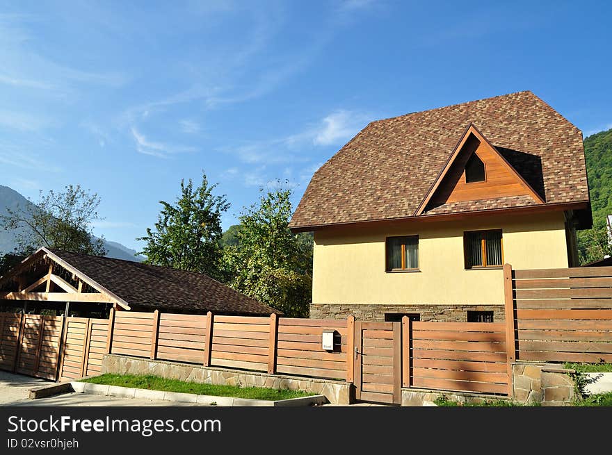 Beautiful big house with a wooden fence on the blue sky background