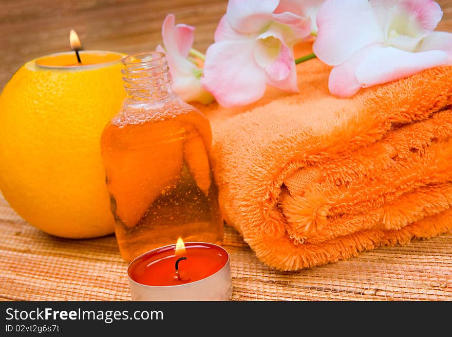 Orange towel, flower and a burning candle in citrus. Orange towel, flower and a burning candle in citrus