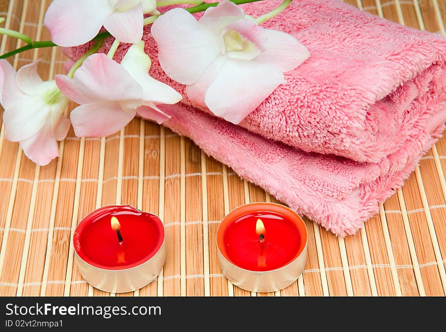 Pink towel, flower and a burning candle. Pink towel, flower and a burning candle