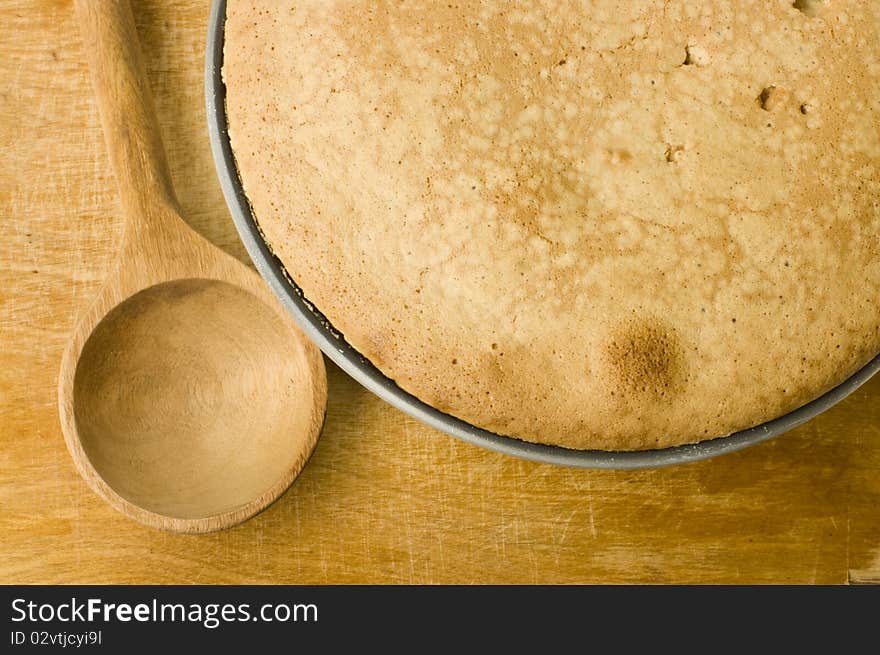 Fresh pie and spoon on a wooden cutting board