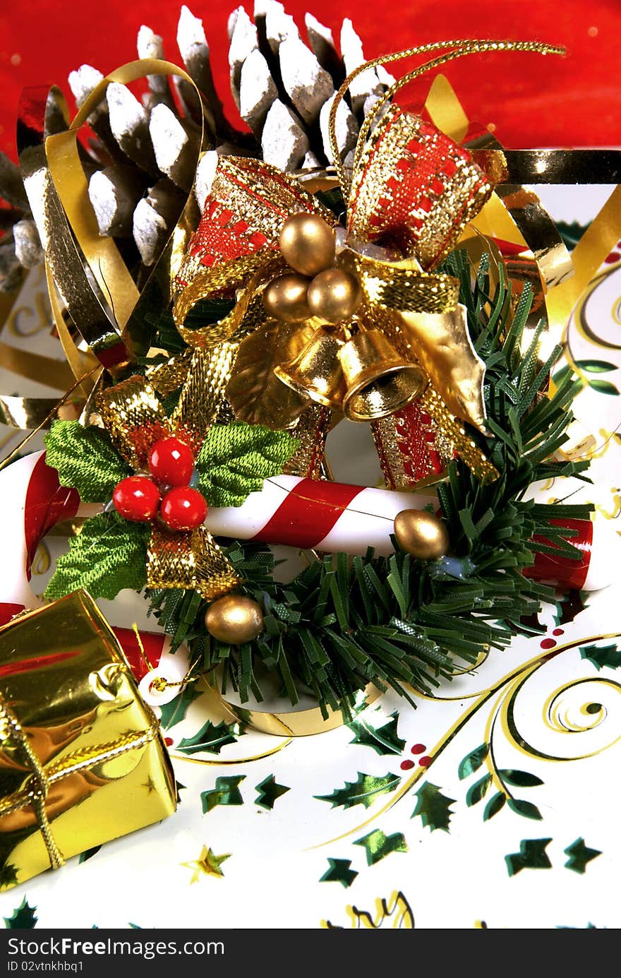 Gold bells, a candy cane and a pine cone on a neatly wrapped christmas present. Gold bells, a candy cane and a pine cone on a neatly wrapped christmas present