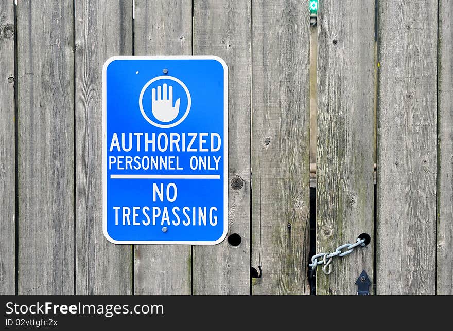 "Authorized Personnel Only" No Trespassing blue sign on a chained wooden door