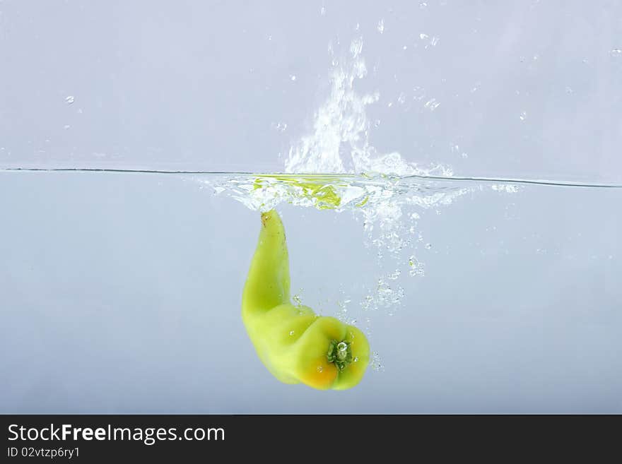 Green Chilli Thrown In Water With Gray Background