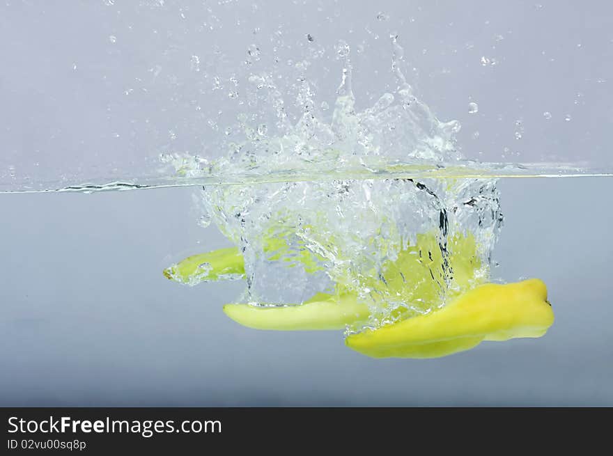 Green Chilli Thrown In Water With Gray Background