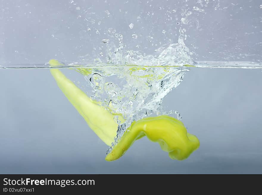 Green chilli thrown in water with gray background