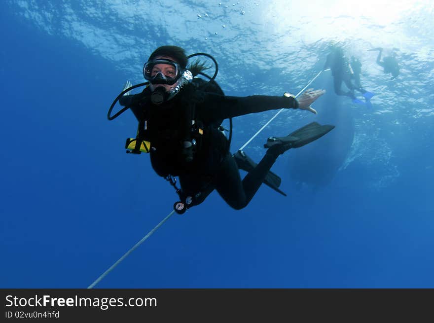 A female diver following an anchor line down to the bottom of the ocean