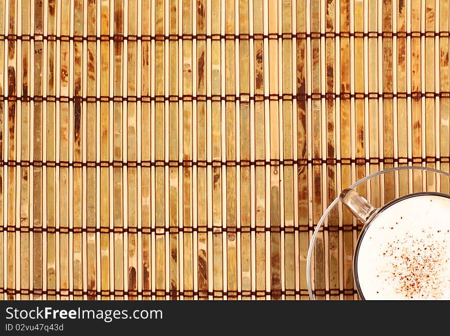 Cup of coffee and beans on bamboo mat