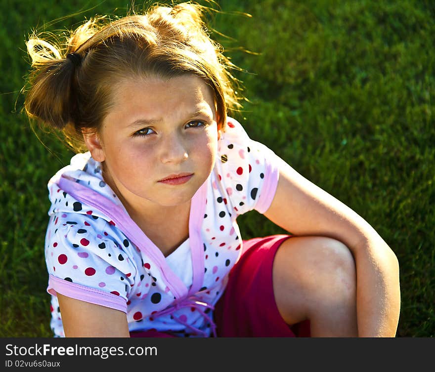 Cute little girl wearing polka dots looking unhappy outdoors. Cute little girl wearing polka dots looking unhappy outdoors.