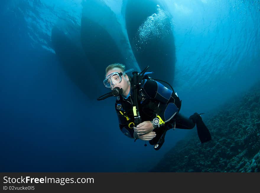 Scuba diver swims under boats