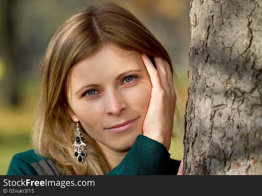 Head portrait of a blonde woman near a tree outdoor. Head portrait of a blonde woman near a tree outdoor