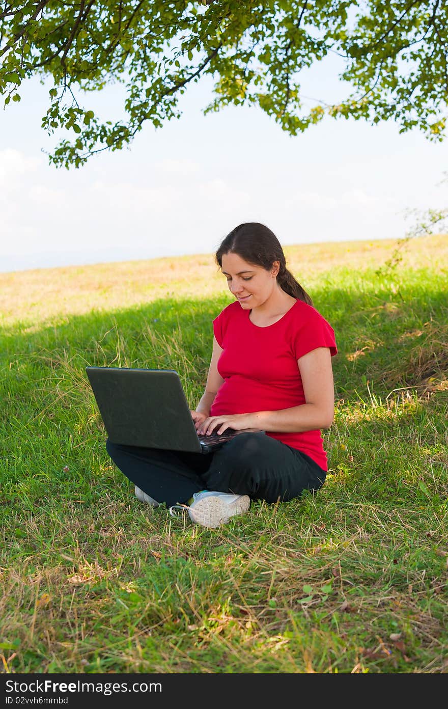 Woman Outdoor using laptop sitting on grass