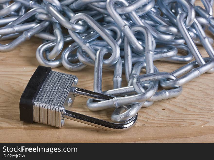 Metal lock and chain on a wooden background.