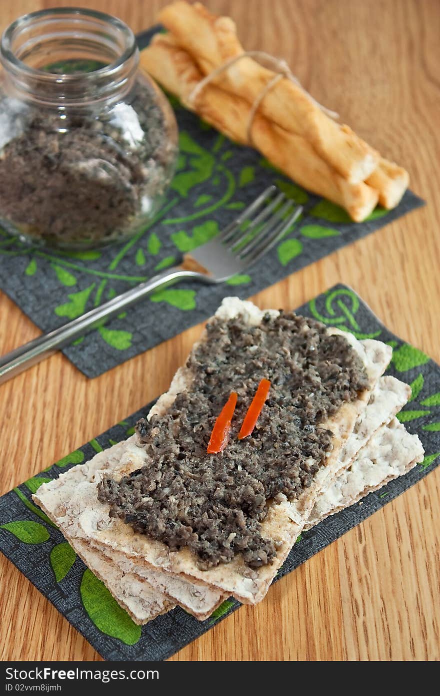 Olives paste on wasa bread on wooden table