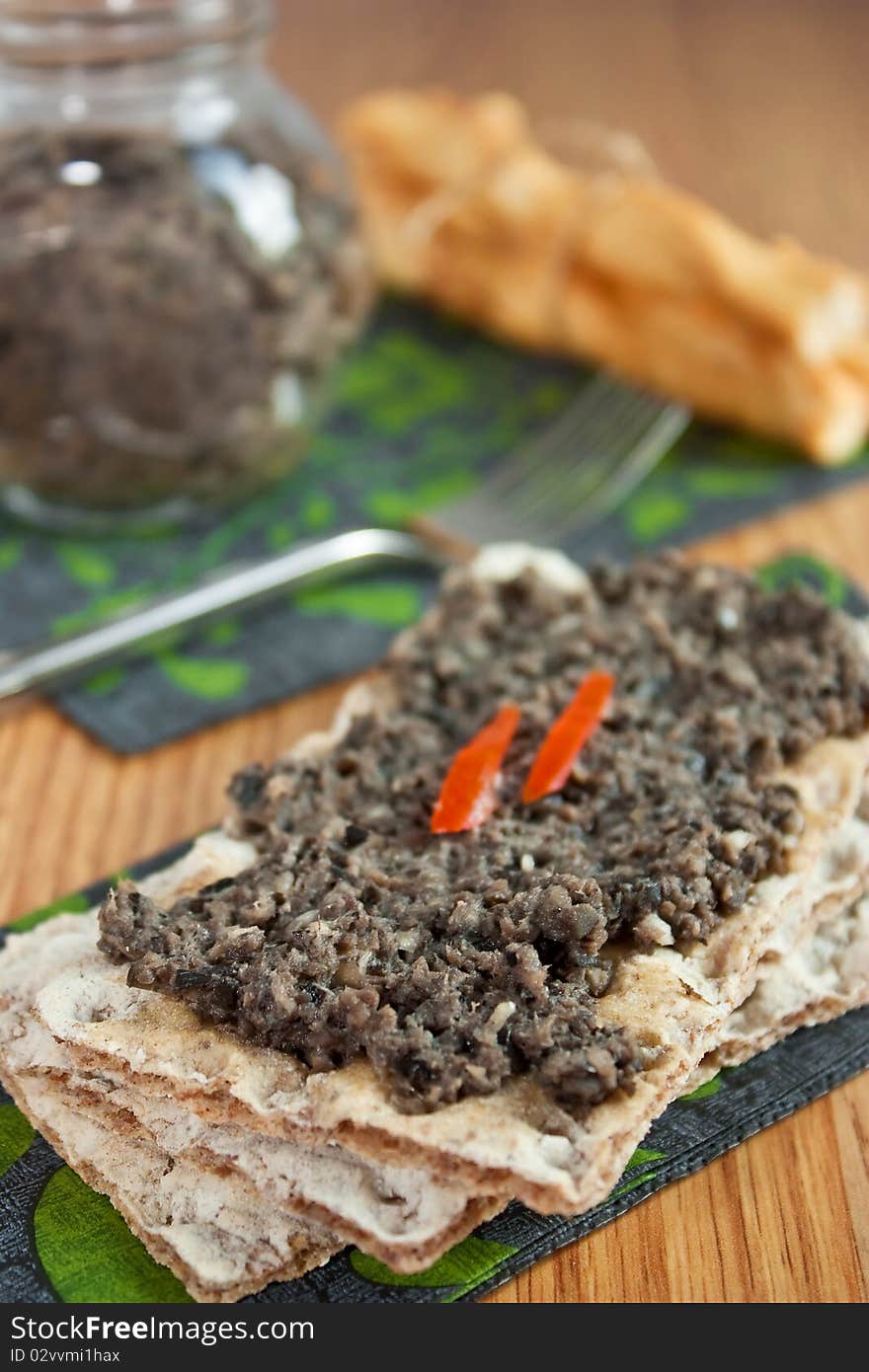 Olives paste on wasa bread on wooden table