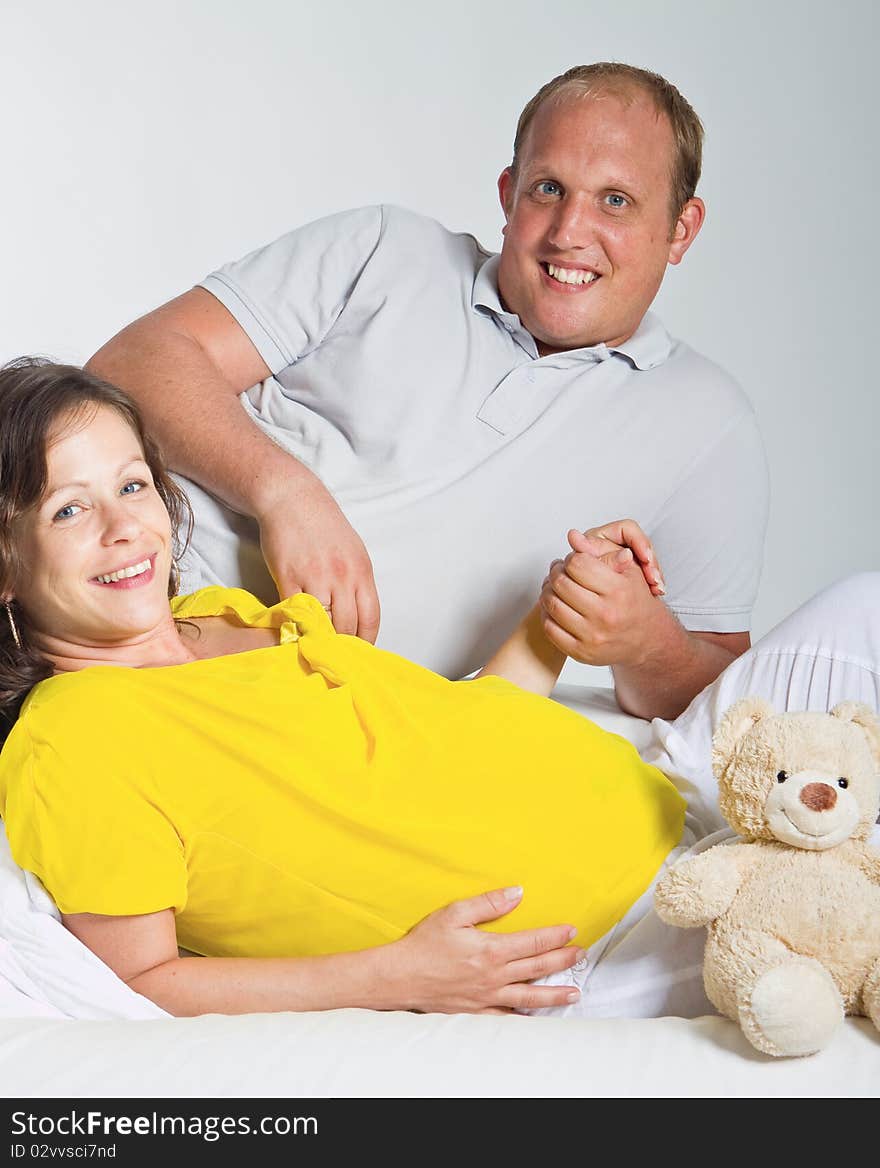 Young couple on a couch. The woman is pregnant and they seem to be in love. Young couple on a couch. The woman is pregnant and they seem to be in love.