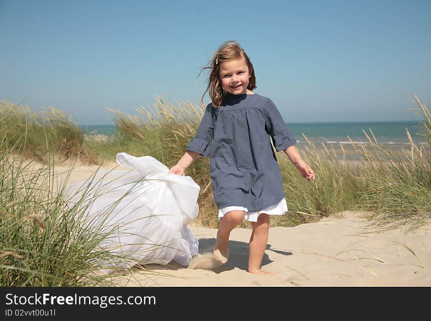 Little girl running on the sand and holding a veil. Little girl running on the sand and holding a veil